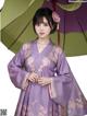 A woman in a purple dress holding an umbrella.