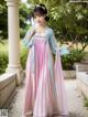 A woman in a pink and blue hanbok is posing for a picture.