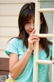 A young woman leaning against a window with her hand on the window frame.