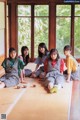 A group of young women sitting on the floor in front of a window.