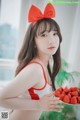 a woman in a red and white bikini holding a plate of strawberries