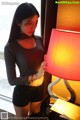 A woman standing next to a lamp in a room.