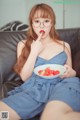 A woman sitting on a couch eating a bowl of strawberries.