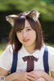 A young woman wearing a cat ears headband and a tie.