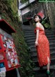 A woman in a red dress standing on some steps.