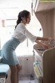 A woman in a white shirt and blue skirt is washing her hands.