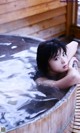 A woman laying in a wooden tub filled with water.