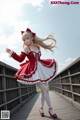 A woman in a red and white dress is standing on a bridge.