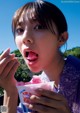 A young girl eating a pink ice cream with a spoon.