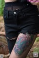 A woman with a tattoo on her leg wearing black shorts.