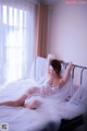 A woman laying on a bed in a white lingerie.