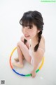 A young woman sitting on the floor with a hula hoop.