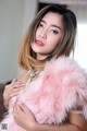 A woman in a pink fur coat posing for a picture.