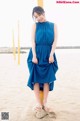 A woman in a blue dress standing on a beach.