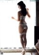 A woman in a white lingerie standing by a window.