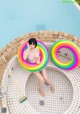 A woman in a bikini sitting in a pool with two inflatable rings.