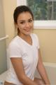 A woman in a white shirt sitting in a bathtub.