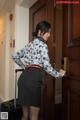 A woman standing in front of a door with a suitcase.