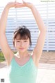 A woman in a green tank top is posing for a picture.