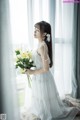 A woman in a white dress holding a bouquet of flowers.