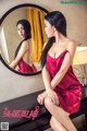 A woman in a red dress sitting in front of a mirror.