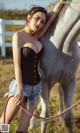 A woman standing next to a white horse in a field.