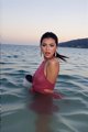 A woman in a red dress standing in the water.