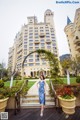 A woman in a blue dress standing in front of a large building.