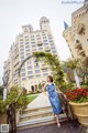 A woman in a blue dress standing in front of a castle.